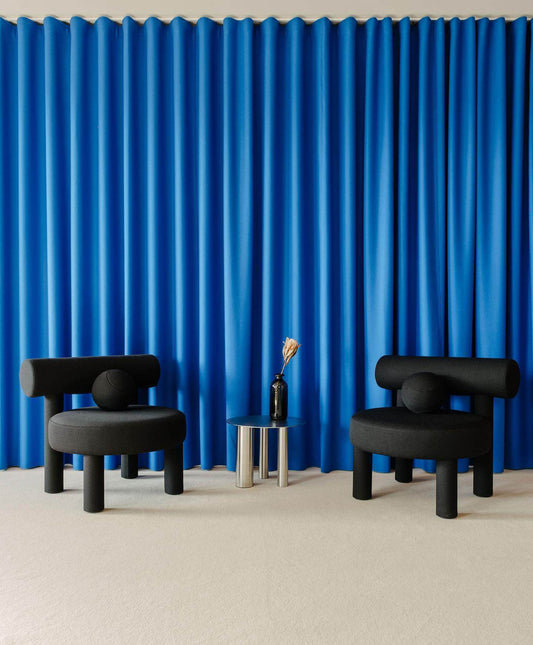 Two Gropius Low Chair CS1 by Noom in front of blue curtain, part of the Bauhaus-inspired collection for modern home design.