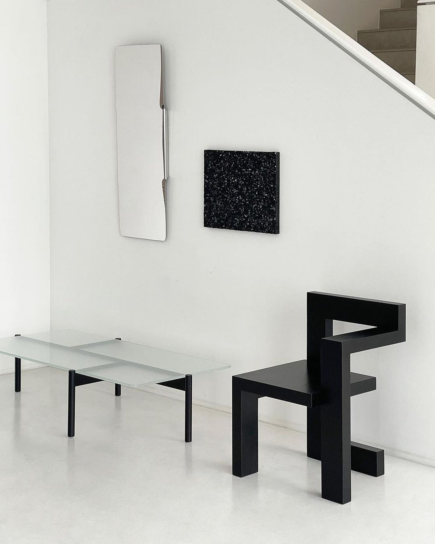 Modern interior featuring a black Steltman chair by Gerrit Rietveld, minimalist glass table, and contemporary wall art.