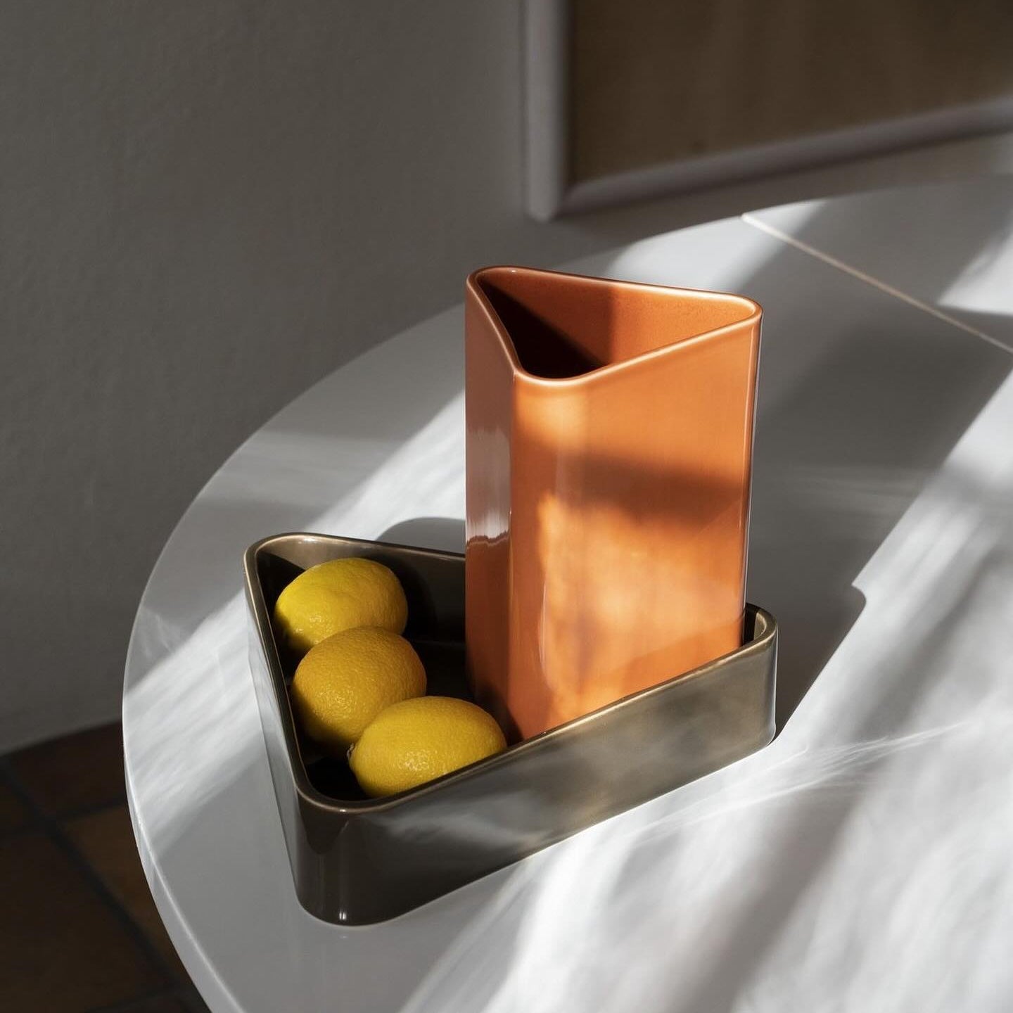 Copper vase and container with lemons on a white surface