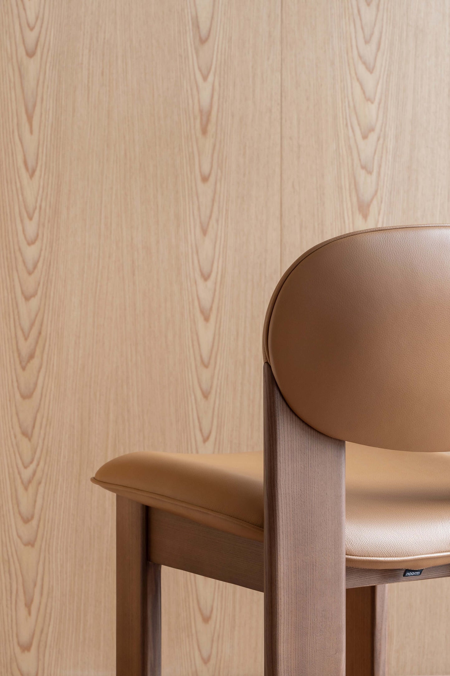 Modern Archipen chair with minimalist design and twisted legs by Noom, inspired by Olexander Archipenko, against wood background.