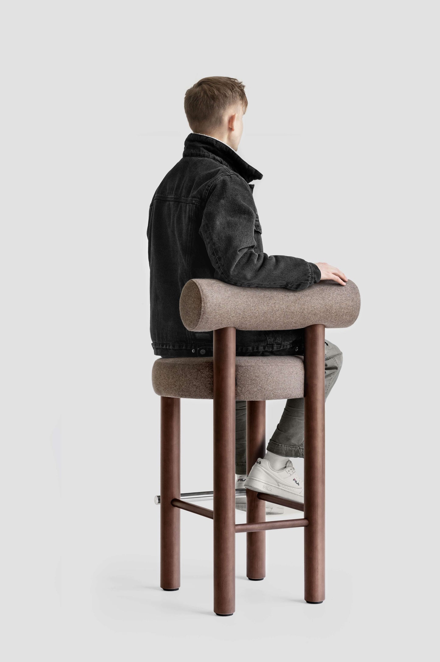 Person sitting on a Gropius CS2 Bar Stool by Noom, designed by Kateryna Sokolova, celebrating Bauhaus design with simple geometric shapes.
