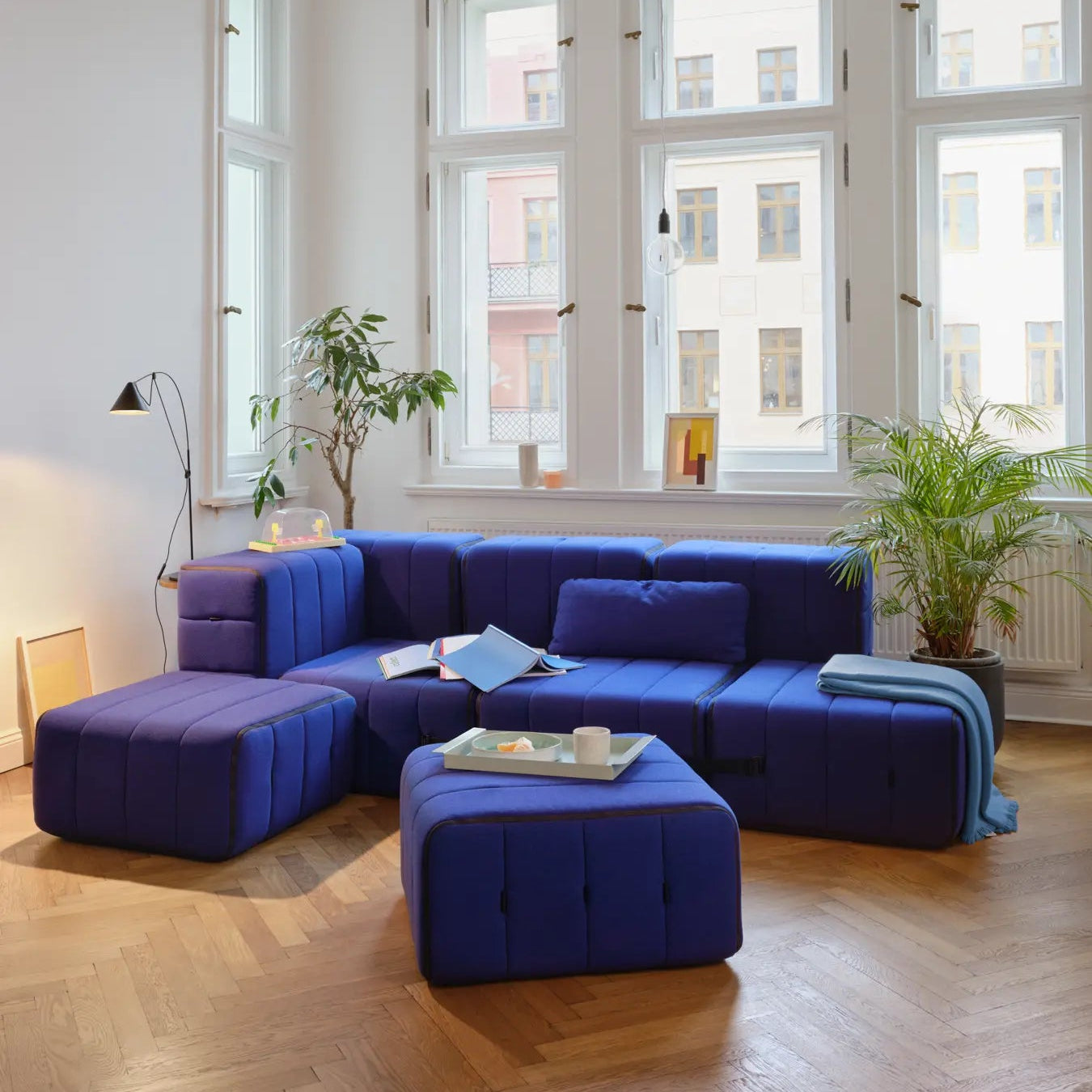 Modern living room with a blue sectional sofa and large windows.