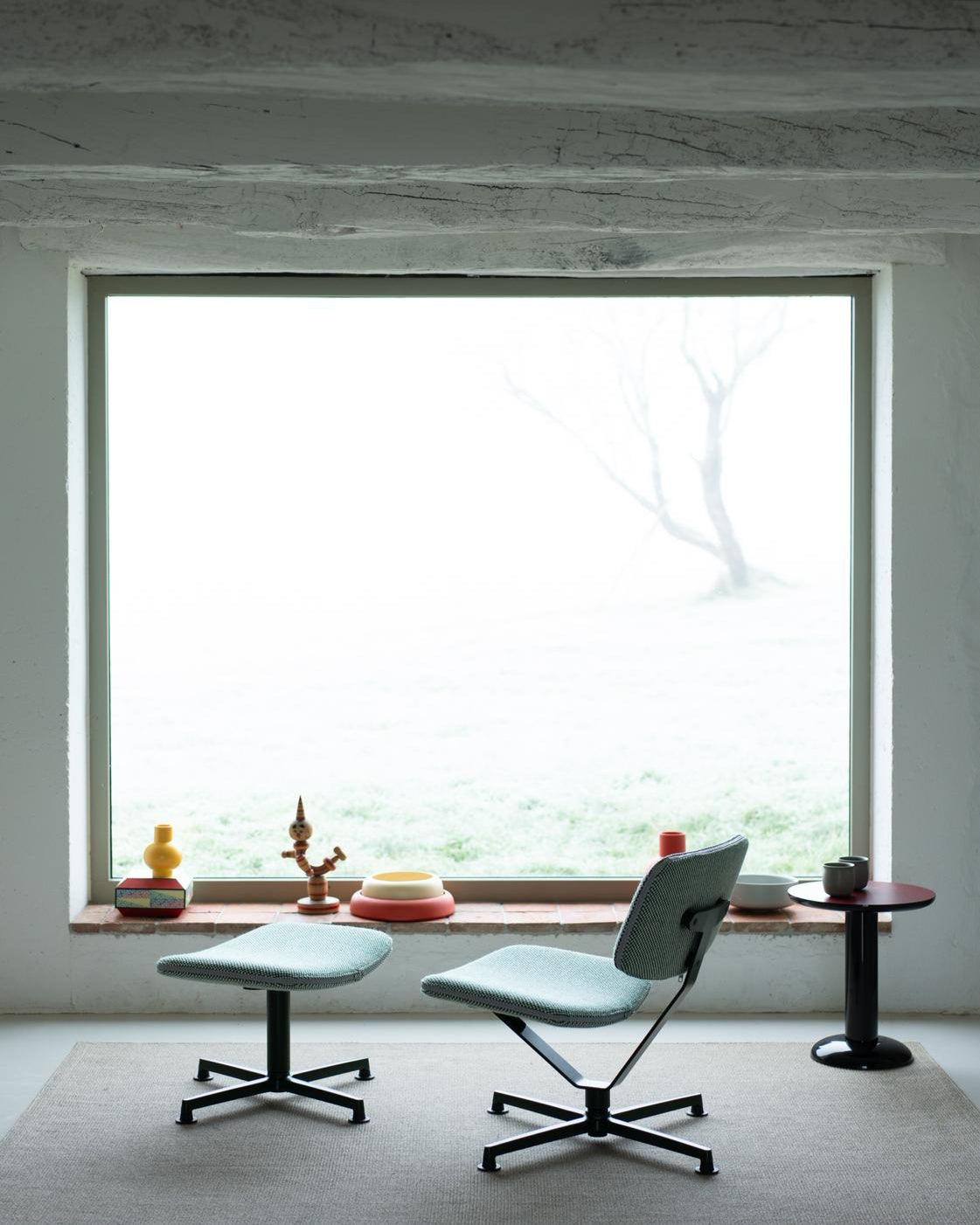 Modern chair and ottoman in a minimalistic room with a large window.