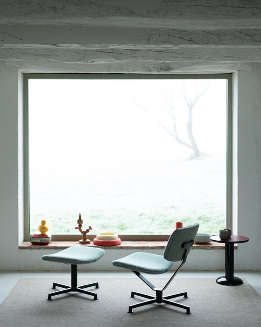 Modern chair and ottoman in a minimalistic room with a large window.