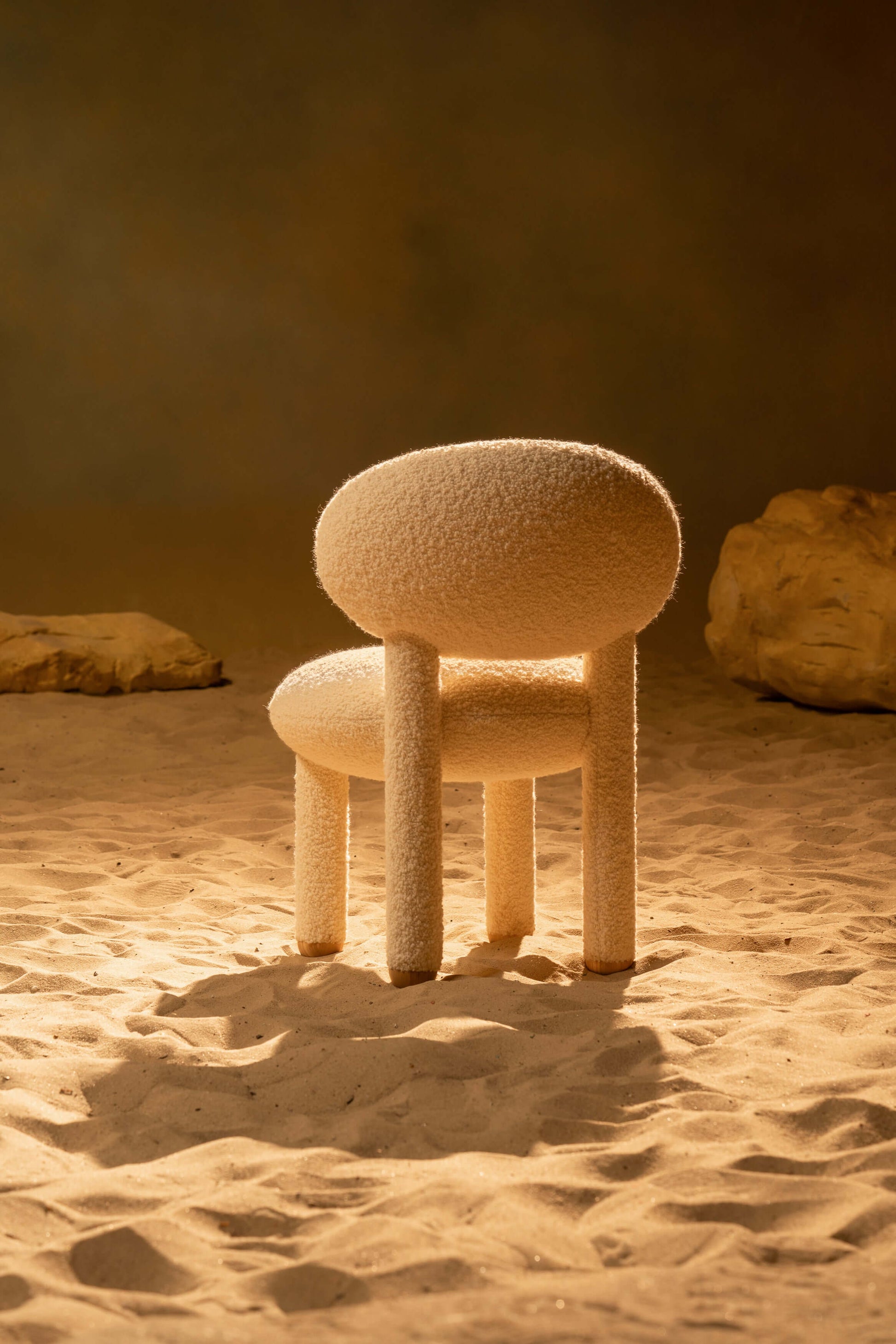 Modern designer Flock dining chair by NOOM Home, showcasing soft, voluptuous forms in a sandy setting.