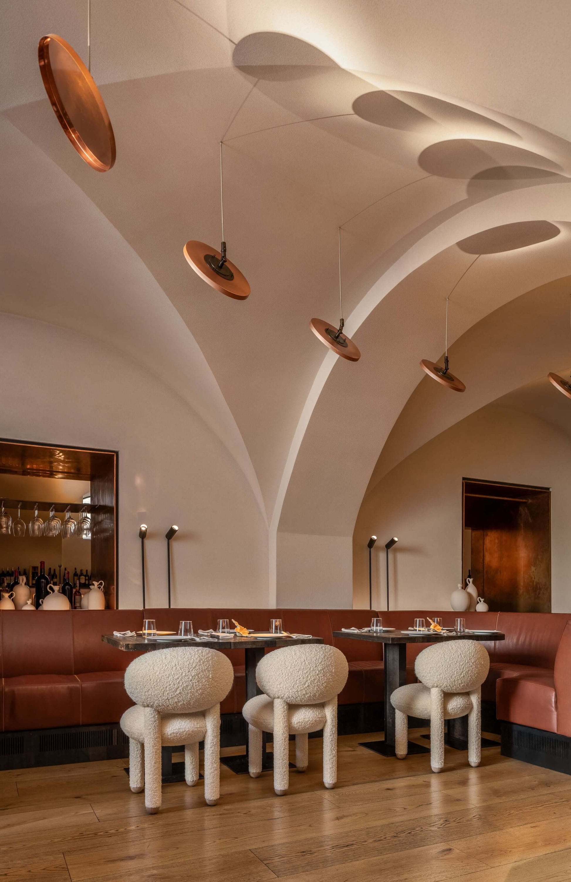 Modern dining room featuring soft Flock CS1 chairs by NOOM, complemented by elegant lighting and arching architecture.