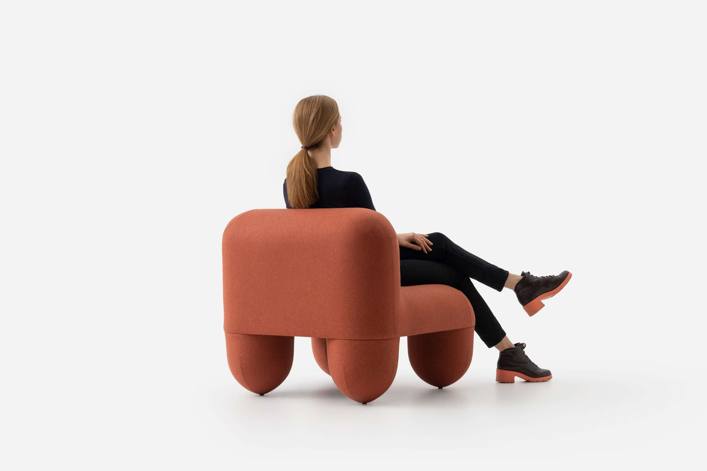 Woman sitting on HELLO Low Chair by Noom, designed by Denys Sokolov, featuring round organic shapes and deep comfortable backrest.