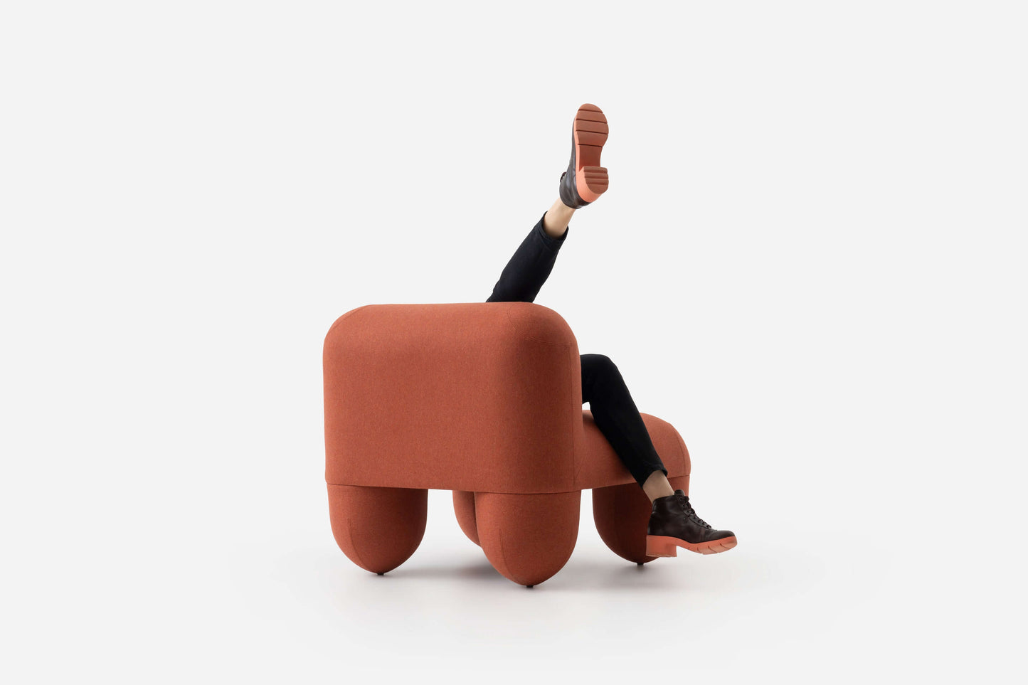 HELLO Low Chair by Noom designed by Denys Sokolov with playful round organic shapes and comfortable seating, featuring person with legs playfully extended.