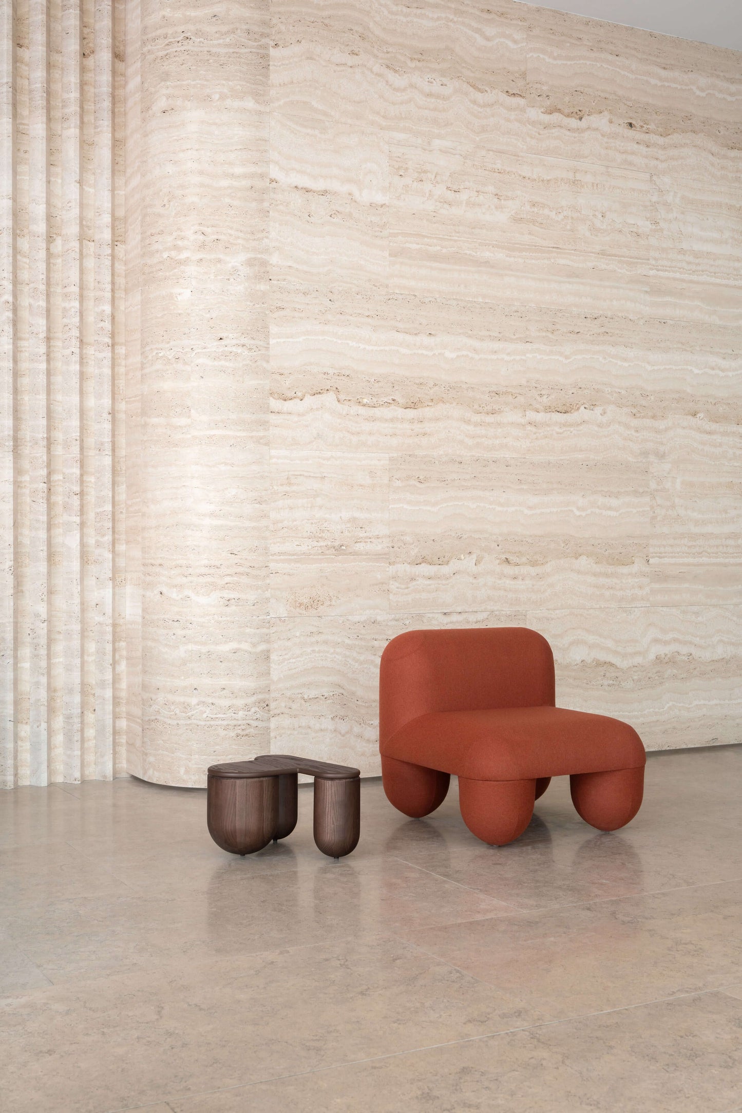 HELLO Low Chair by Noom designed by Denys Sokolov, featuring playful round shapes and deep comfort, next to a small wooden table.
