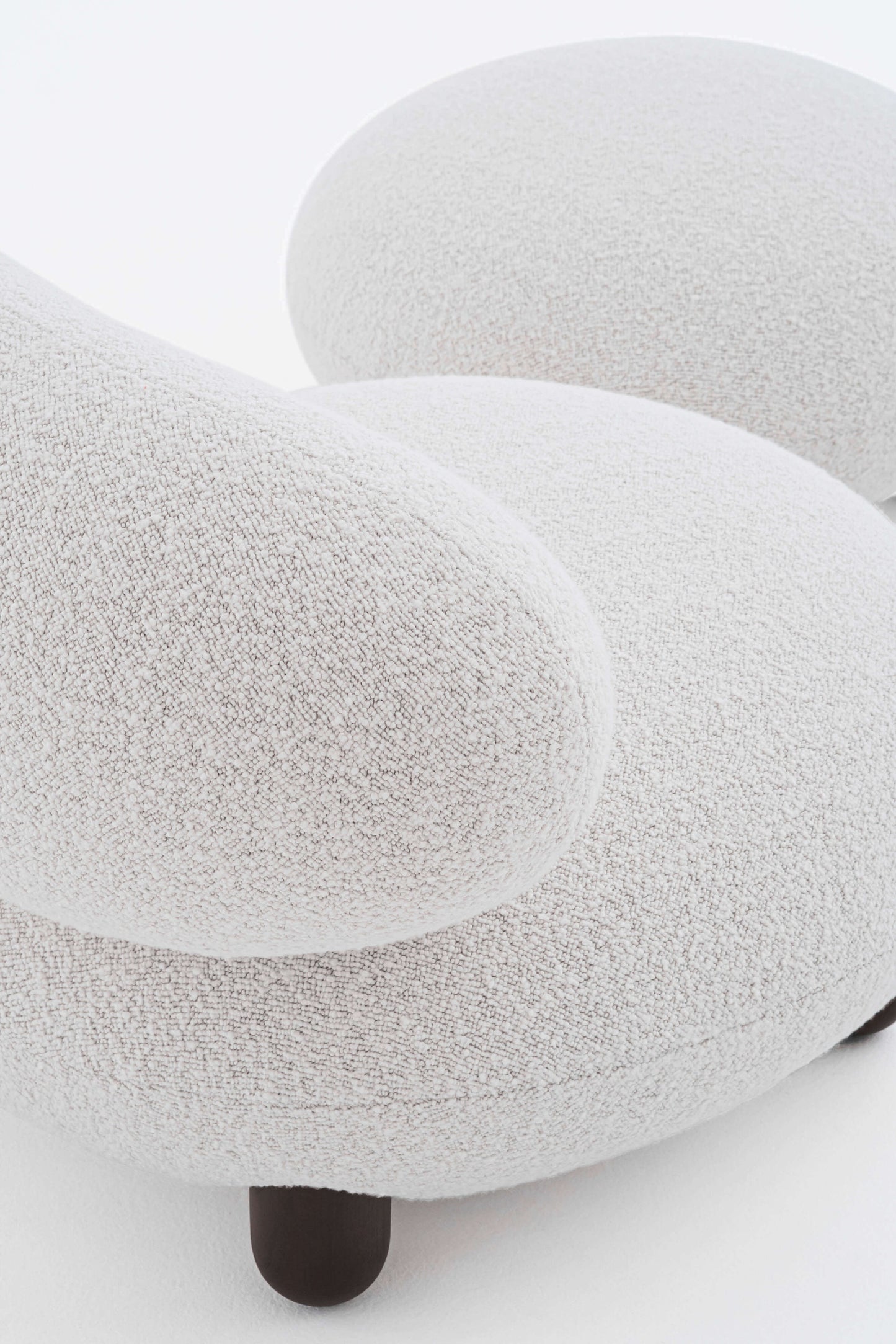 Elegant close-up of the Flock Lounge Chair by Noom, showcasing cozy curves and a textured fabric for home comfort.