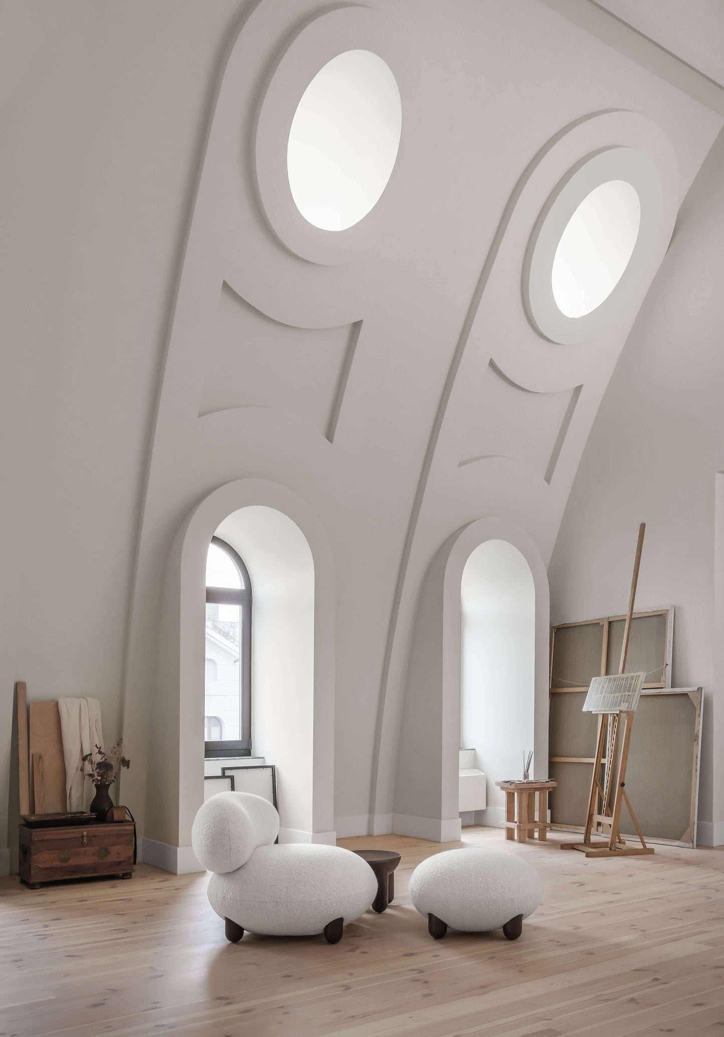 Elegant white Flock lounge chairs by Noom in a modern, minimalist room with artistic decor and arched windows.