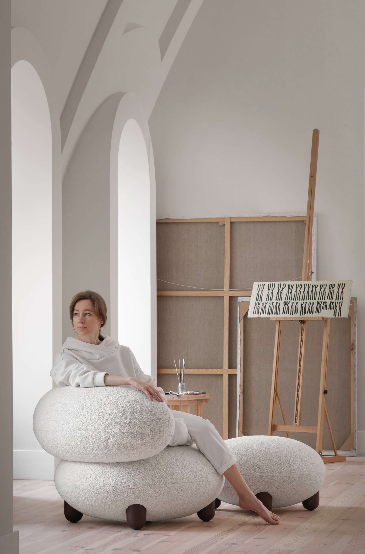 Woman sitting on Flock lounge chair by Noom in a cozy, art-filled room.