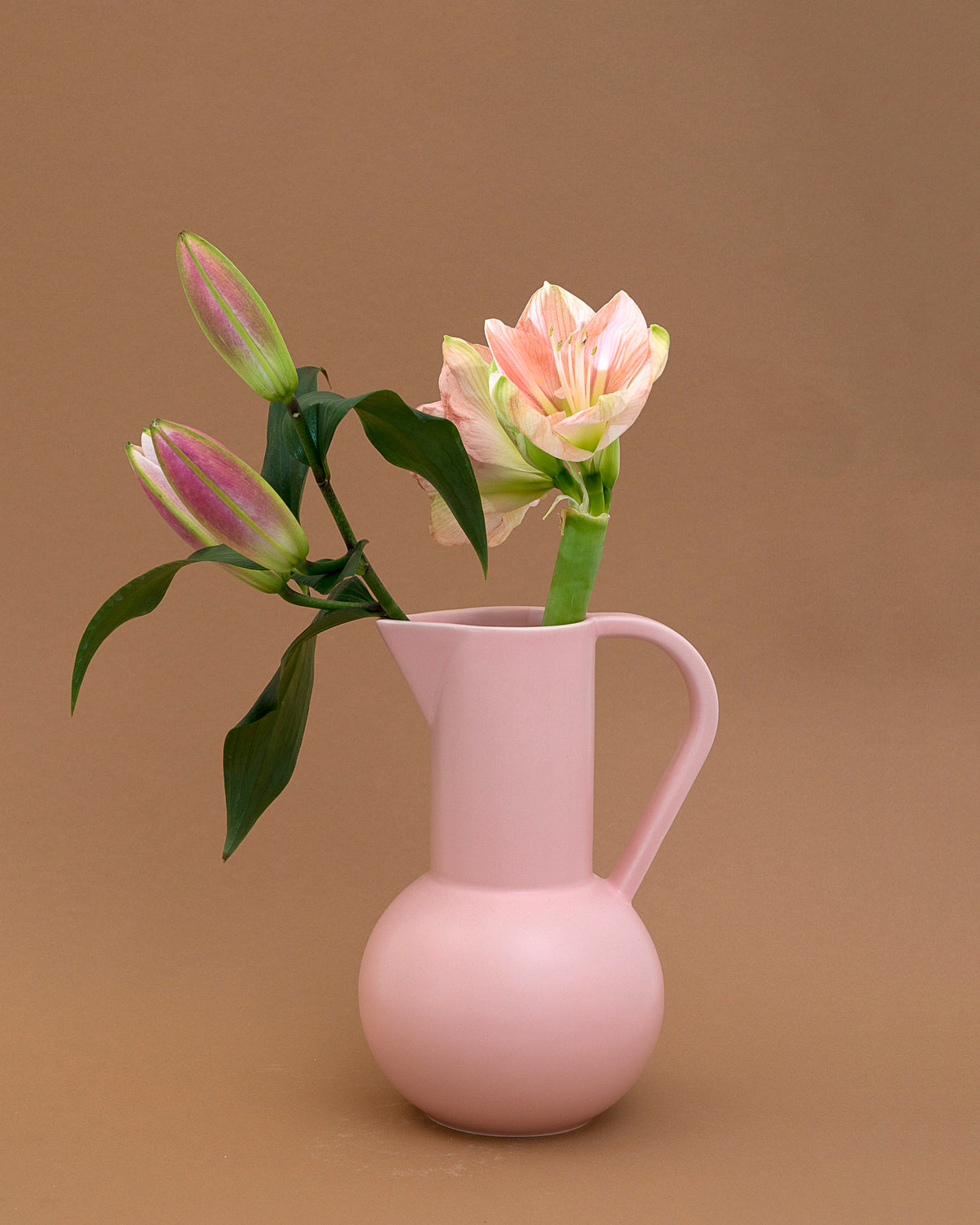 Pink ceramic pitcher with flowers on a brown background