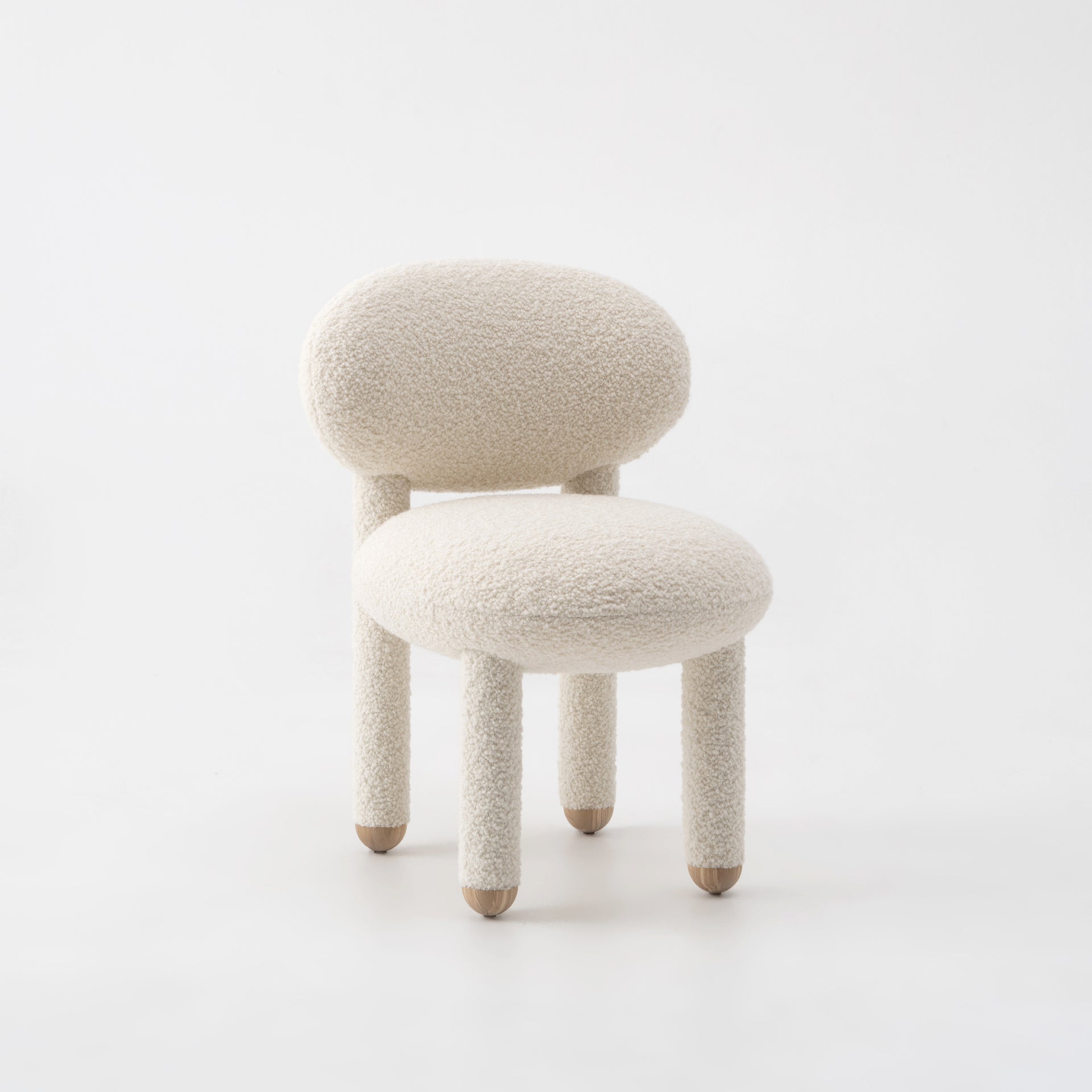 Modern designer Flock dining chair by NOOM home, featuring soft, plush upholstery and rounded forms in a neutral color.