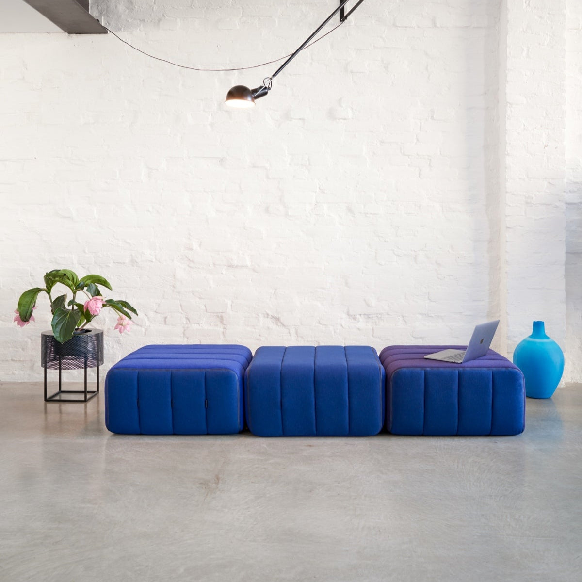 Modern blue sofa in a minimalistic room with white walls and concrete floor.