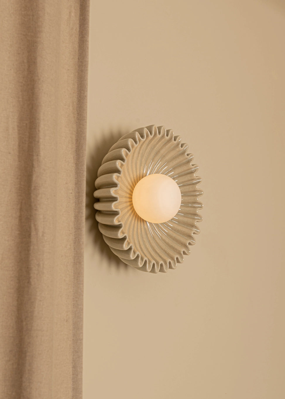 Designer circular wall sconce with textured shade and warm glow, perfect for adding elegance to any interior space.