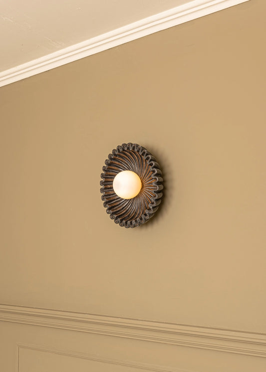 Designer marble circular wall sconce by Simone et Marcel, featuring a unique spiraled design and warm diffused light.