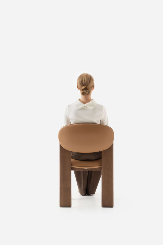 Minimalist Archipen chair by Noom with a person seated, showcasing flat twisted legs inspired by Ukrainian avant-garde design.