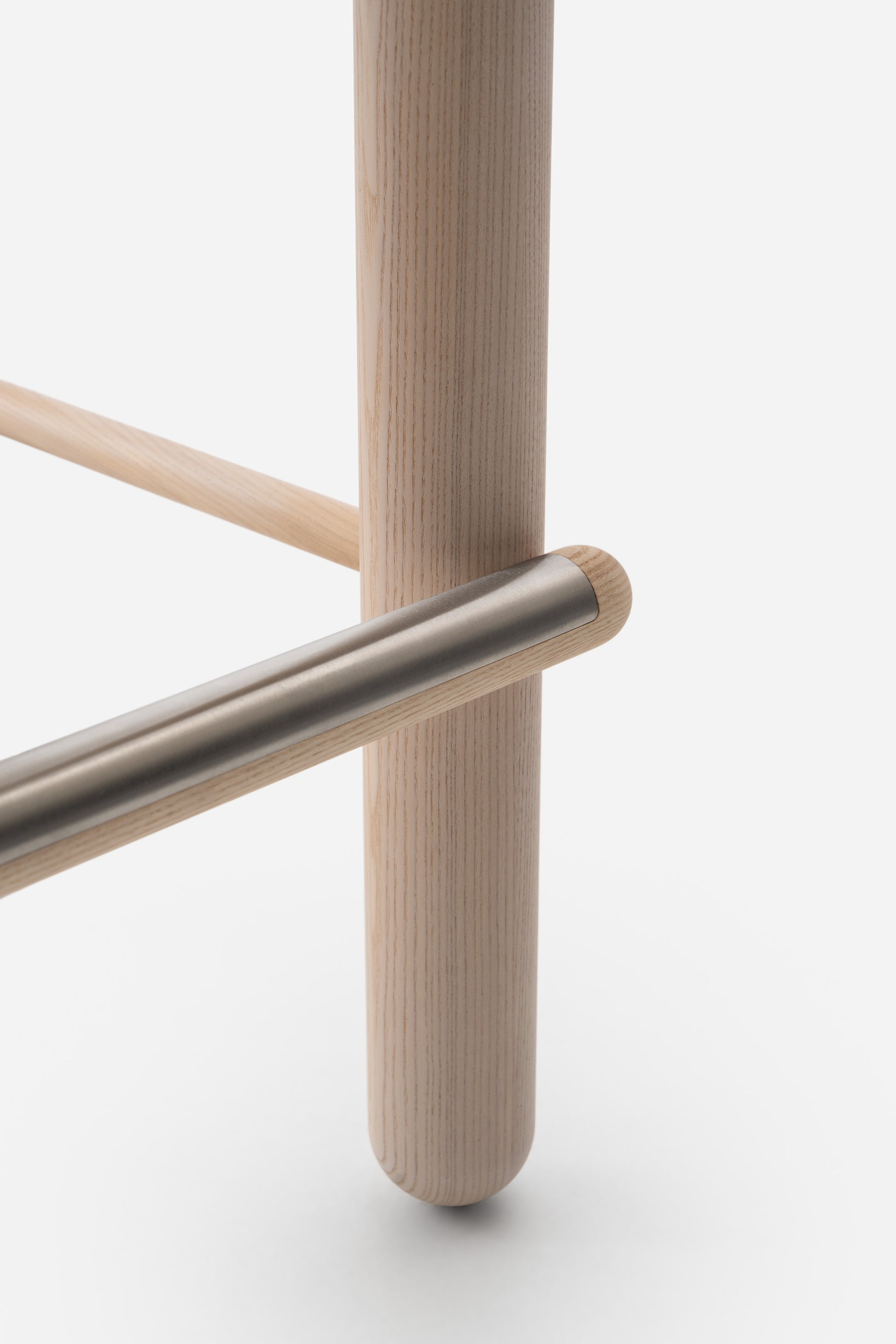 Close-up of Flock CS2 Bar Stool's wooden leg and metal footrest detail, showcasing modern design by NOOM.