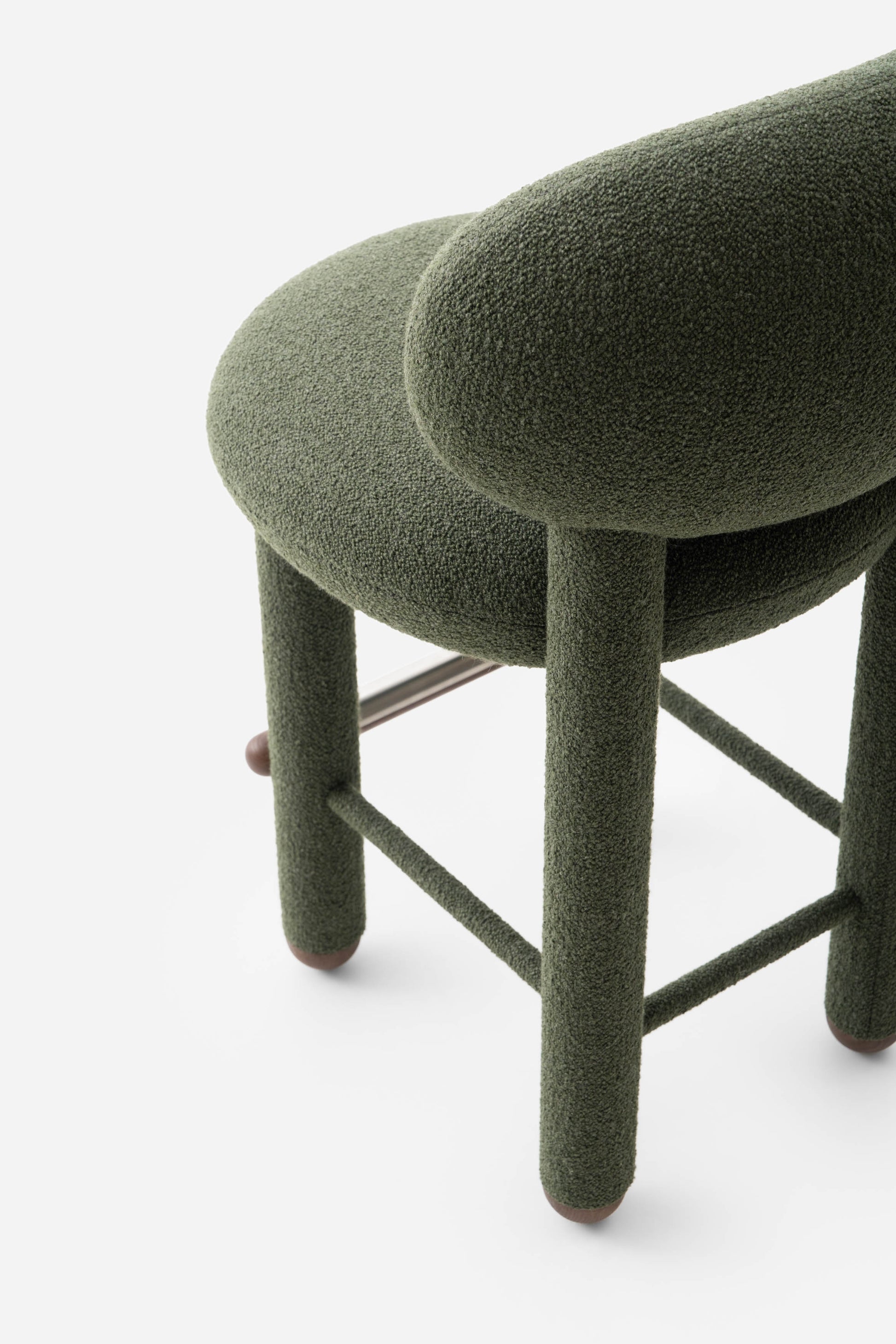 Modern designer Flock CS1 bar stool by Noom, showcasing deep green fabric, curved back, and sturdy legs.