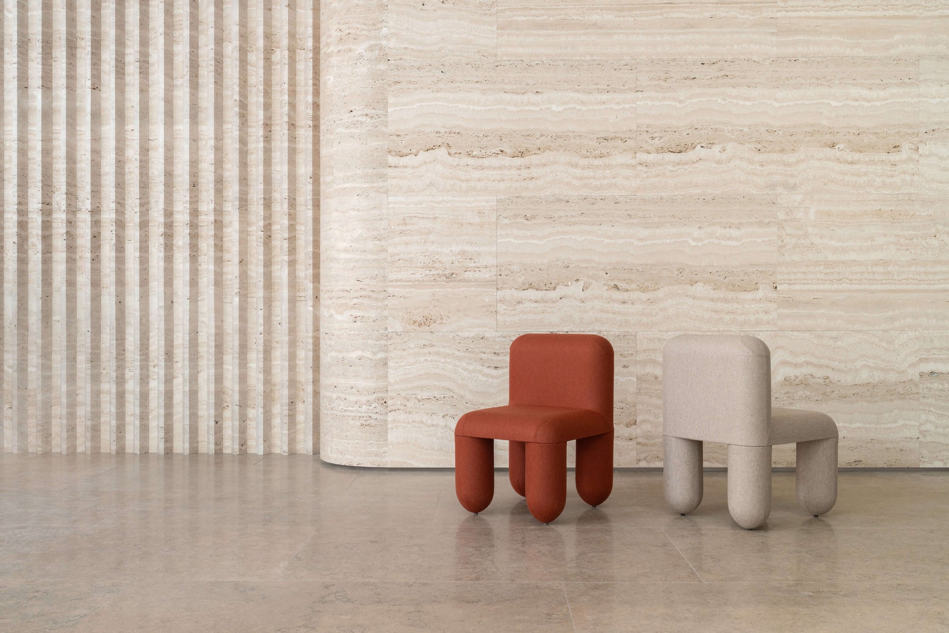 Modern HELLO chairs by Noom in red and beige against a textured wall, showcasing organic design and comfort for home interiors.