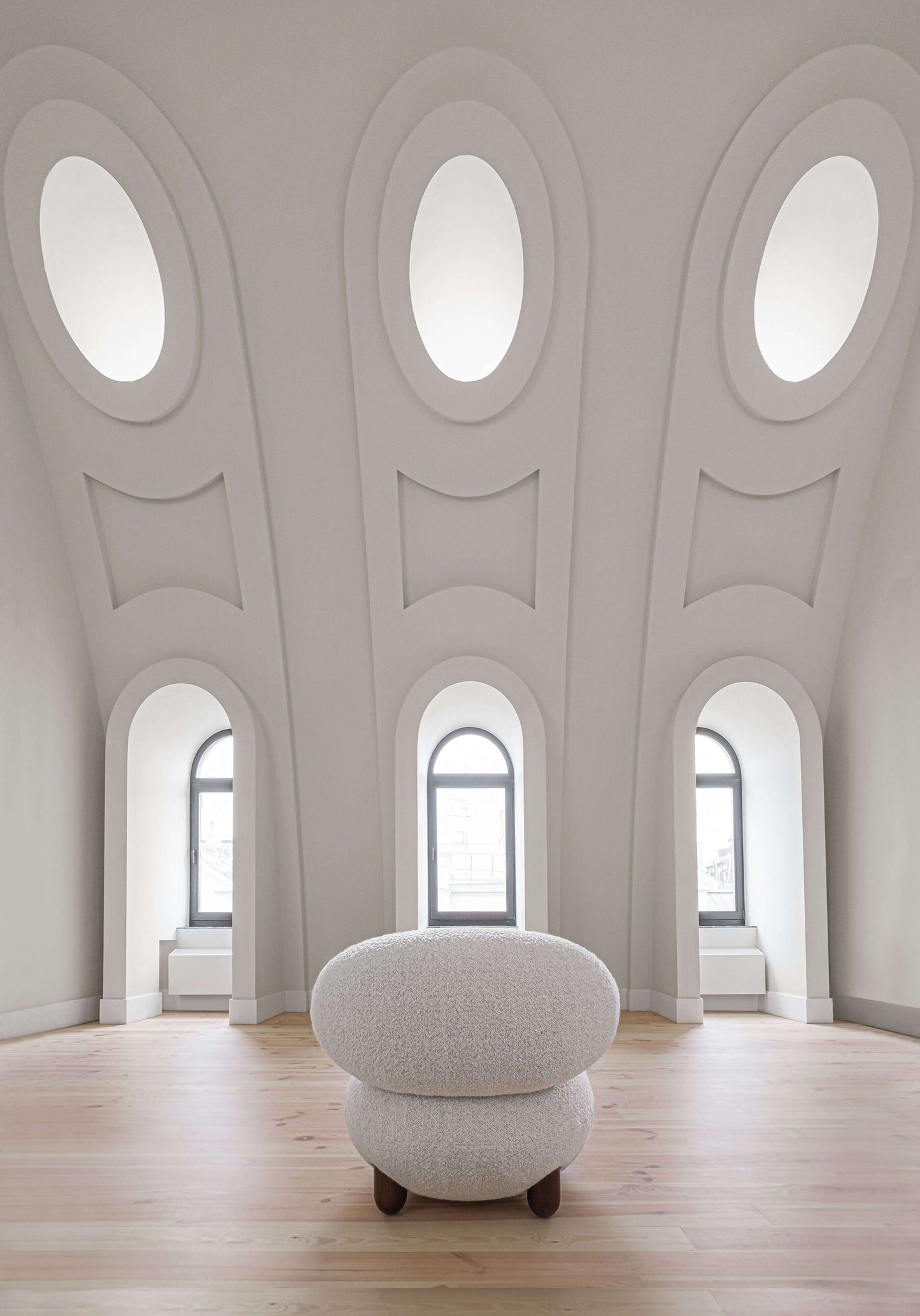 Flock lounge chair by Noom in an elegant room with arched windows and minimalist decor.