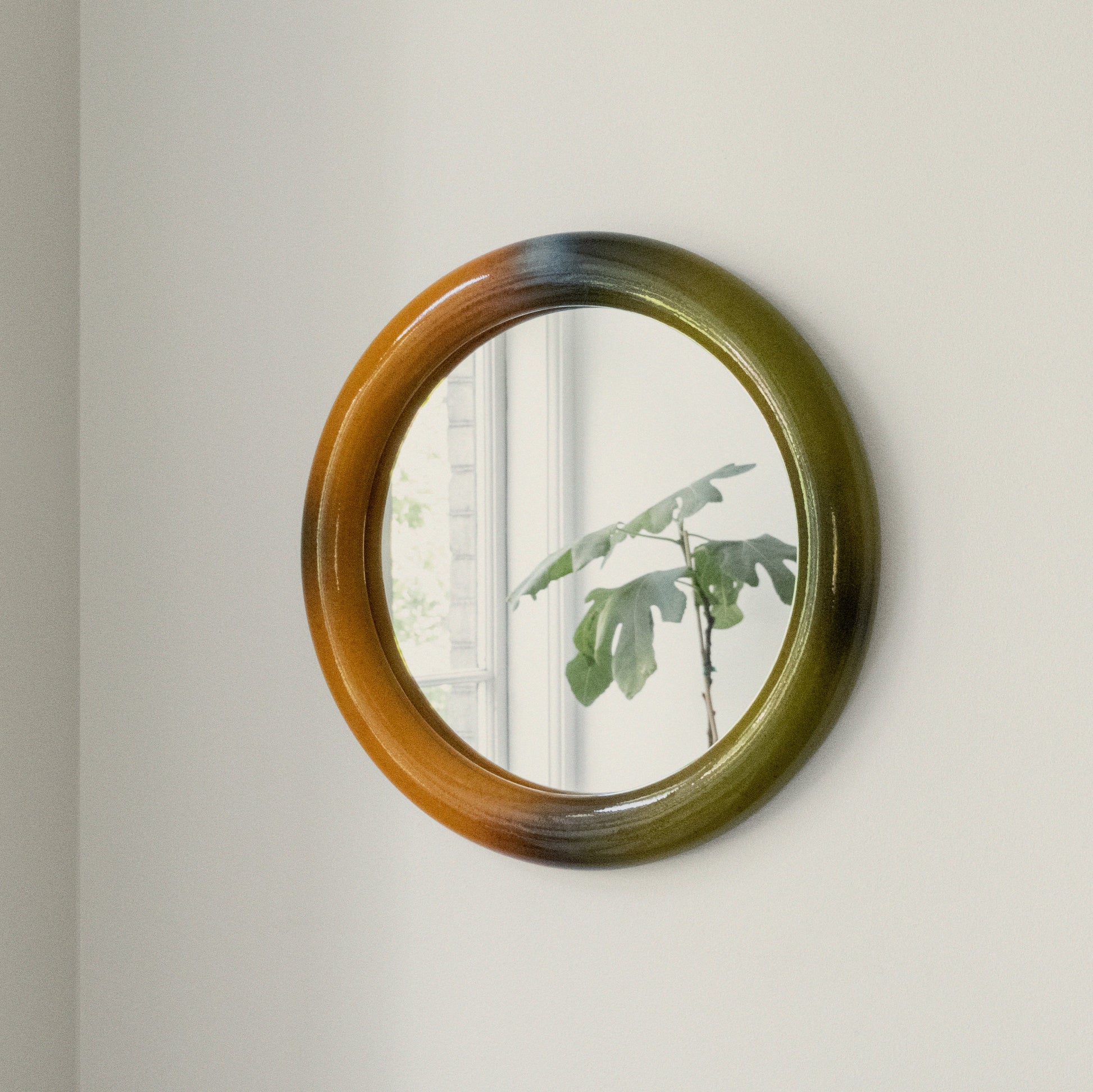 Round mirror with a gradient frame on a plain wall