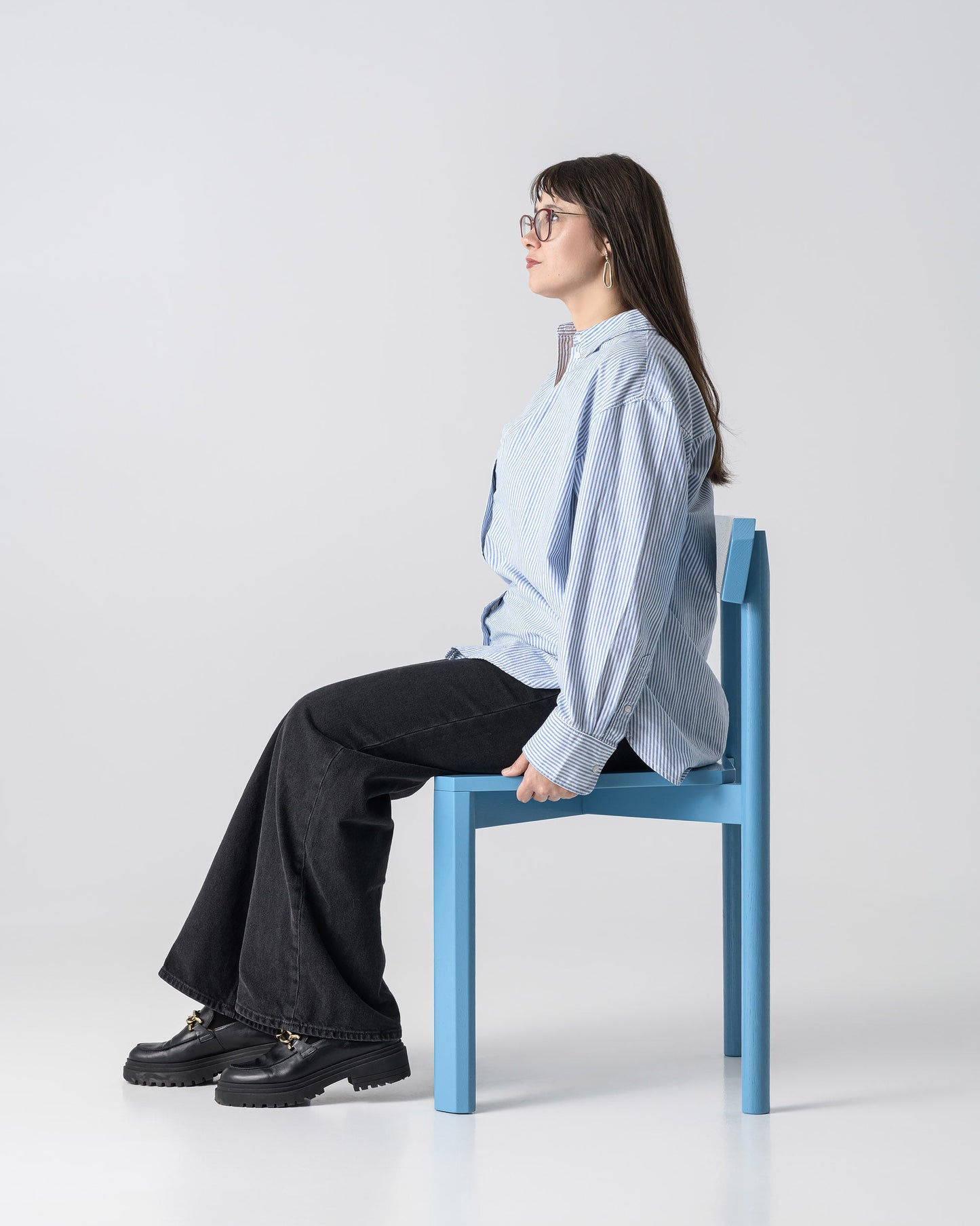Person sitting on a blue chair against a white background