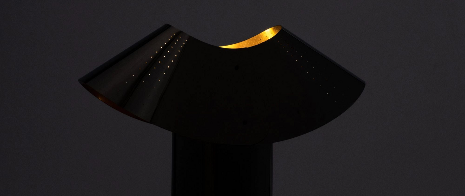 Modern black table lamp with a gold interior on a dark background