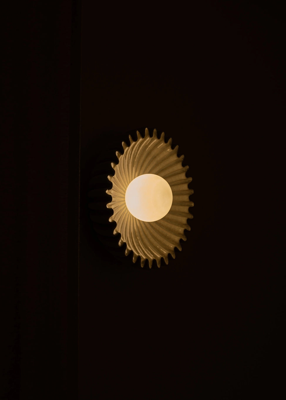 Designer marble circular wall sconce by Simone et Marcel with warm light and unique textured design.